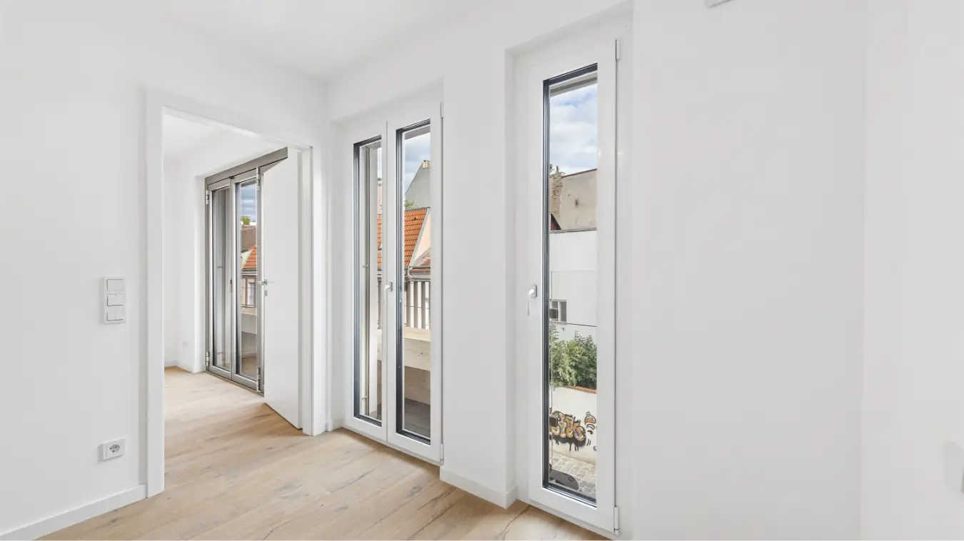 Heller Flur mit Holzboden und Fenstertüren zu einem Balkon/Terrasse.
