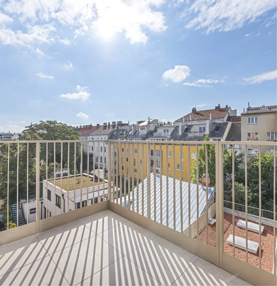 Balkon mit hellem Geländer und weitem Blick über die Stadt und Dächer.